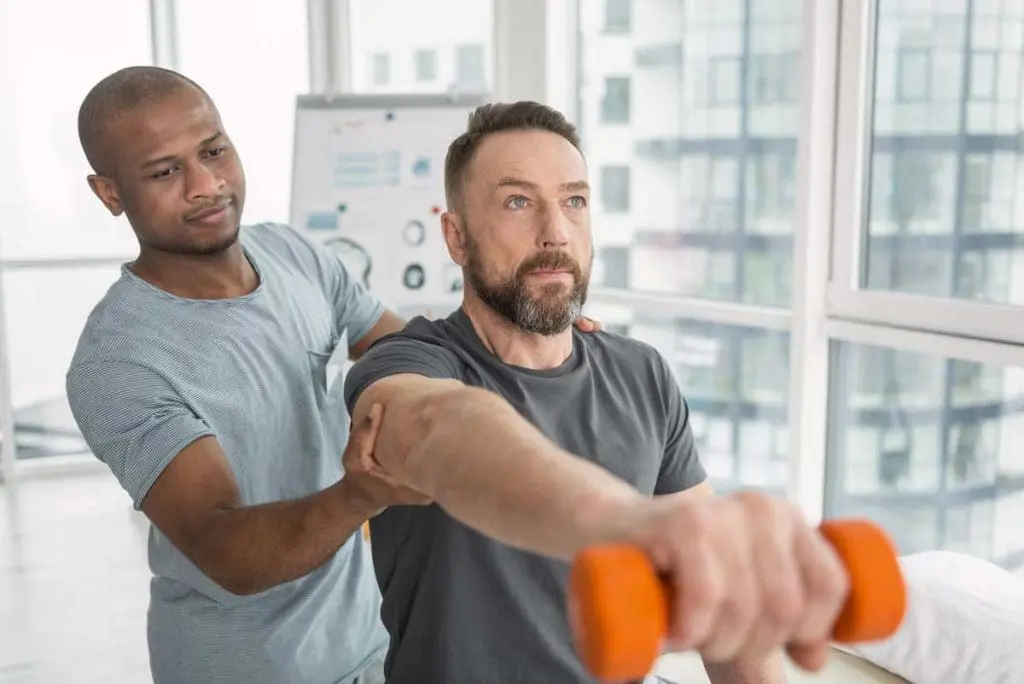 Worker lifting weight under physiotherapist's supervision, representing strength test in OGUK physical exams