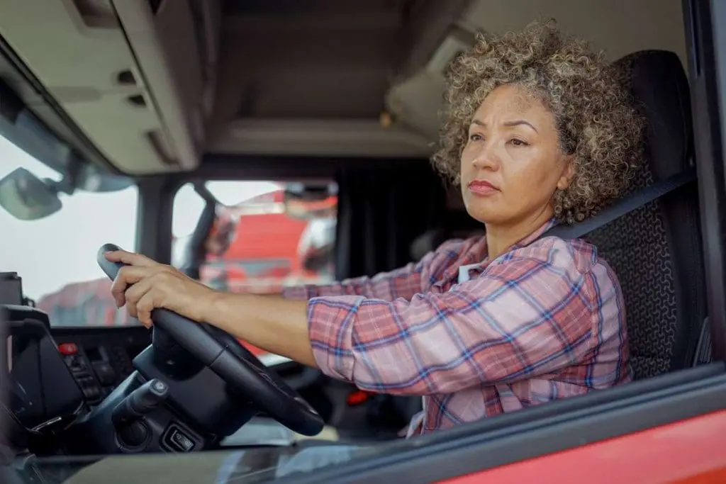 Female truck driver introspectively looking out the window, pondering about CDL and mental health.