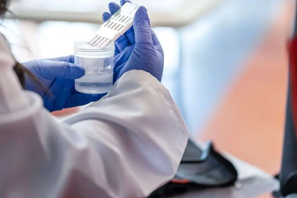 Scientist in white coat conducting an MRO drug test procedure