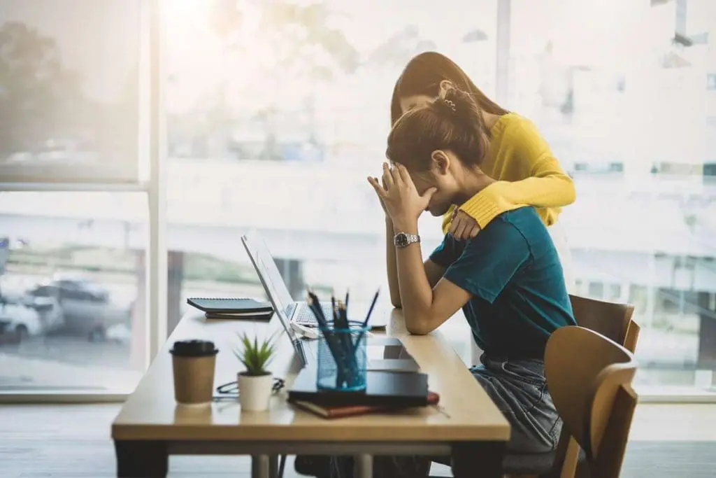 Colleague supporting another at work, showing concern for mental health.