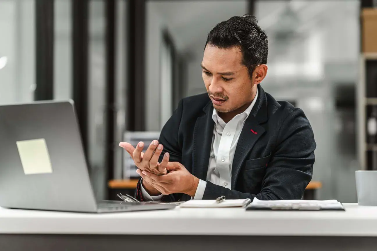 Office worker experiencing wrist pain, a common workplace-related musculoskeletal condition.