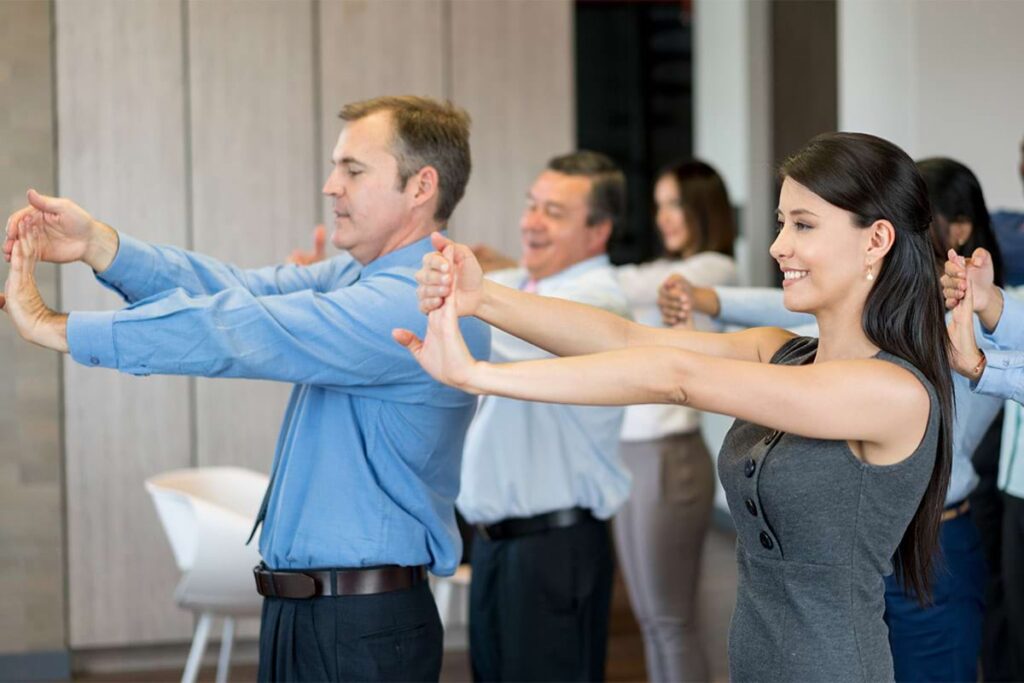 Employees participating in group stretching exercises as part of a workplace health program.