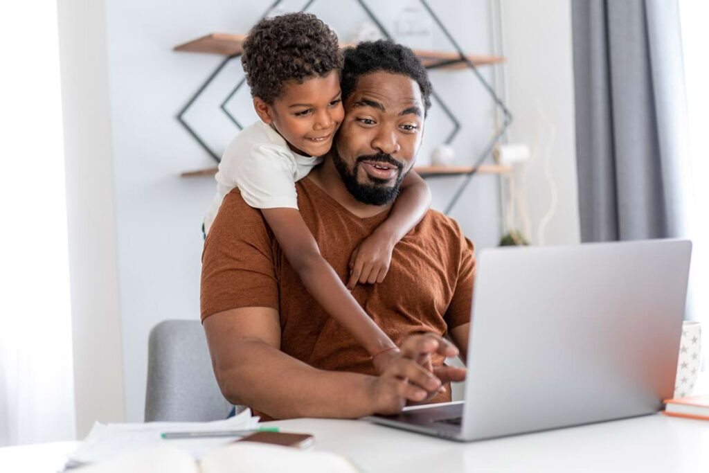 Father working from home with his child, demonstrating work-life balance.