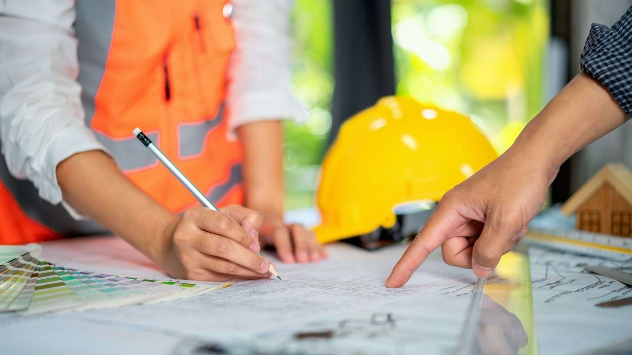Engineer’s hands pointing at project drawings with pencil