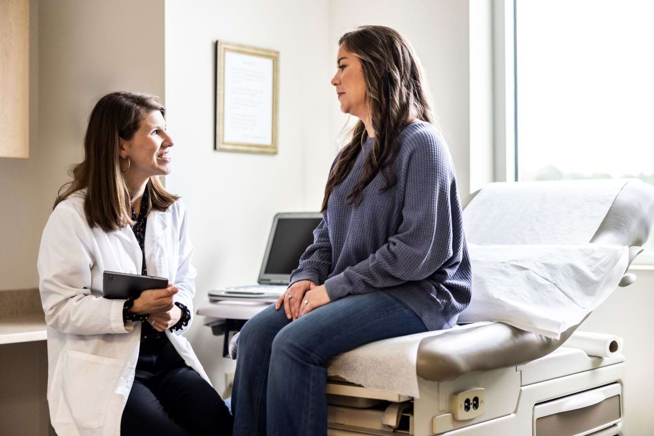 Female occupational medicine physician attentively speaking with a patient during a clinical consultation.